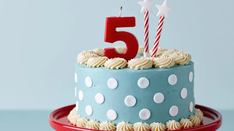 Light blue polka dot birthday cake with red number five candle and star candles on red tray