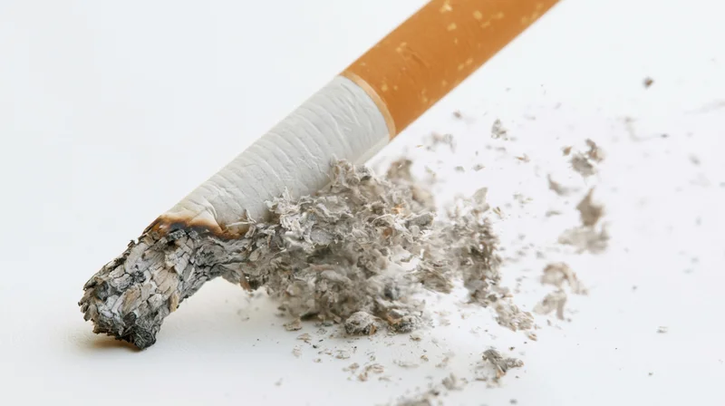 Cigarette stub with ash and debris exploding outward on white background