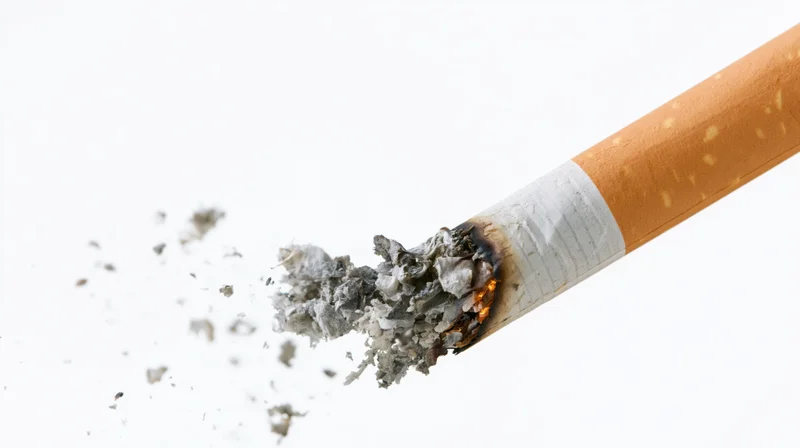 Lit cigarette with burning tip and ash falling against white background
