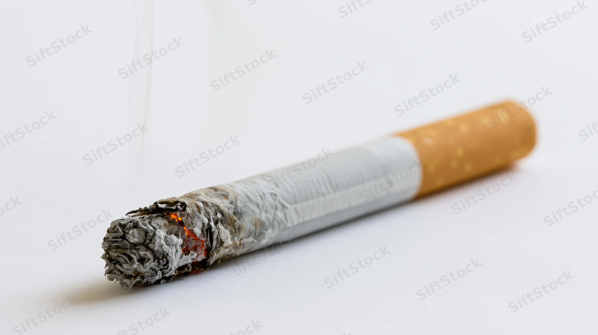 Lit cigarette with ash and smoke on white background