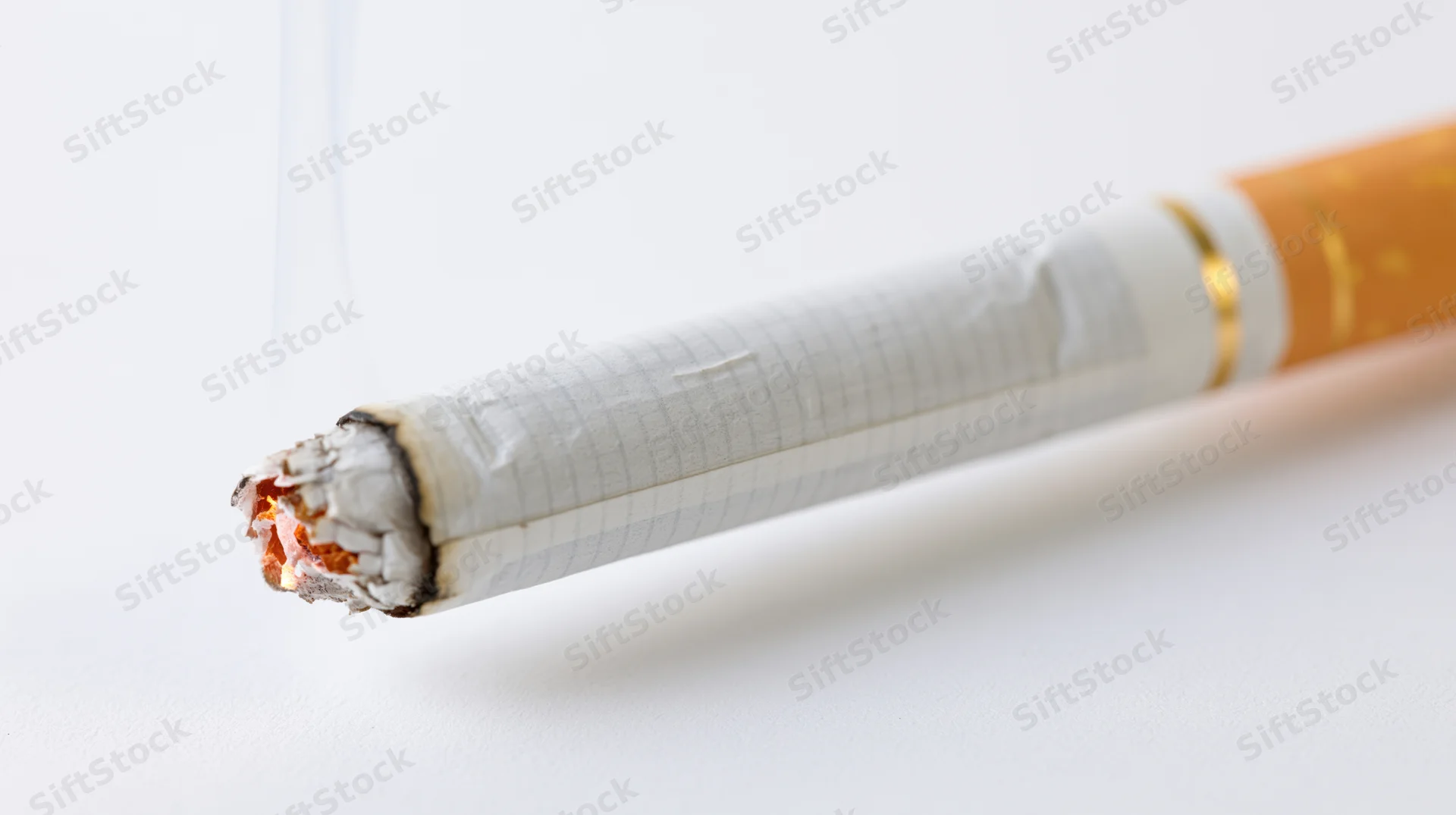 Lit cigarette with glowing ember and ash on white background