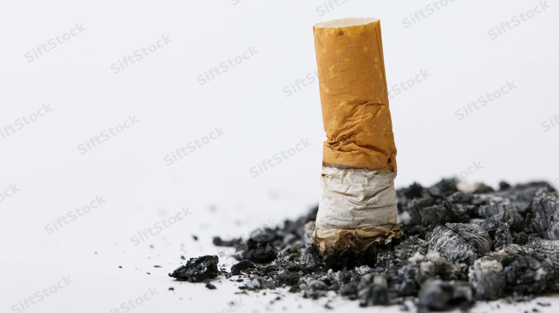 Stubbed-out cigarette butt standing upright on a pile of ash against a white background