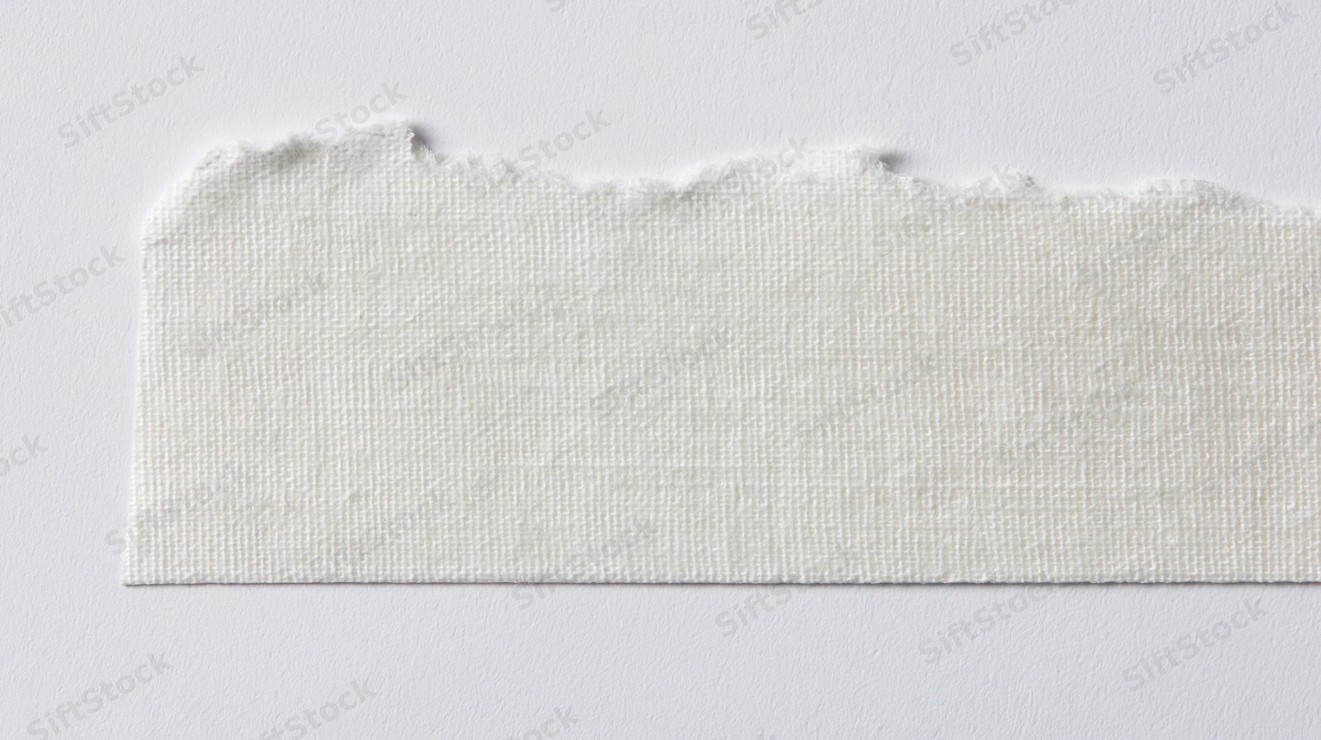 Torn strip of white adhesive tape on a plain surface