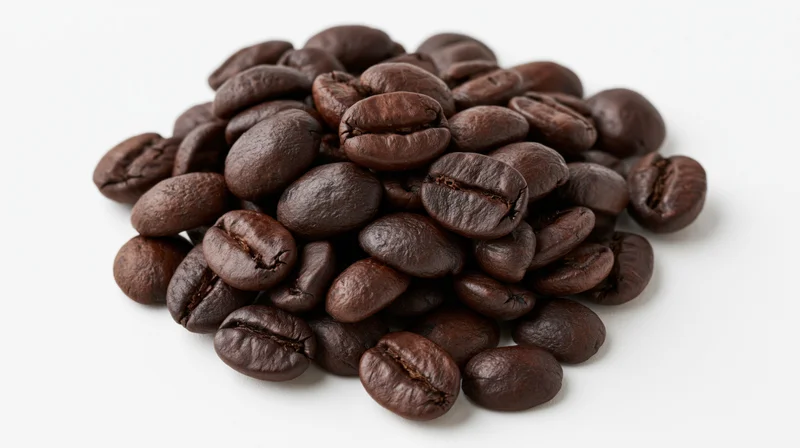 Small loose pile of dark-roasted coffee beans heaped on white background