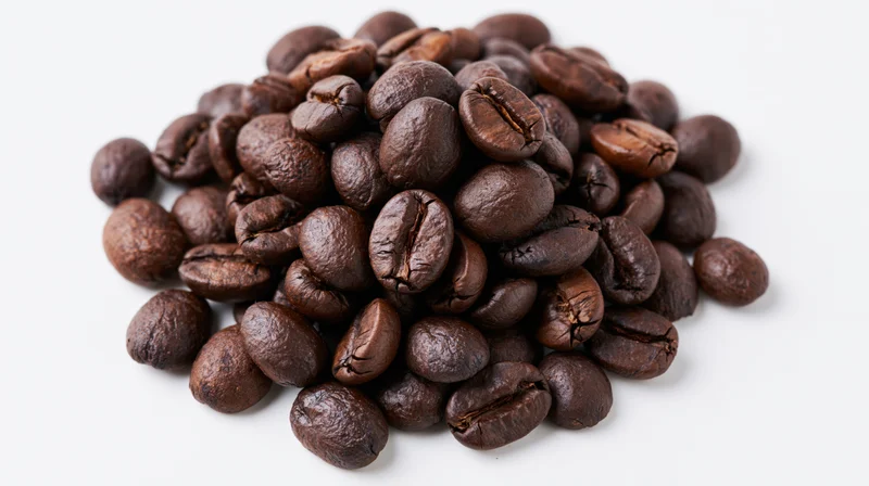 Dark roasted coffee beans piled on white background