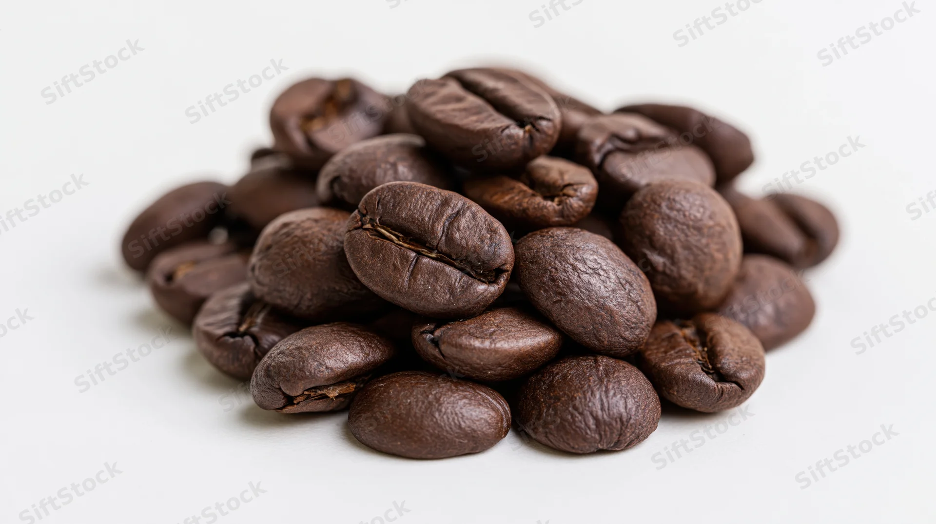 Pile of dark roasted coffee beans on white background