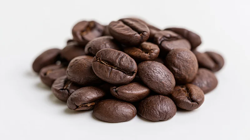 Pile of dark roasted coffee beans on white background