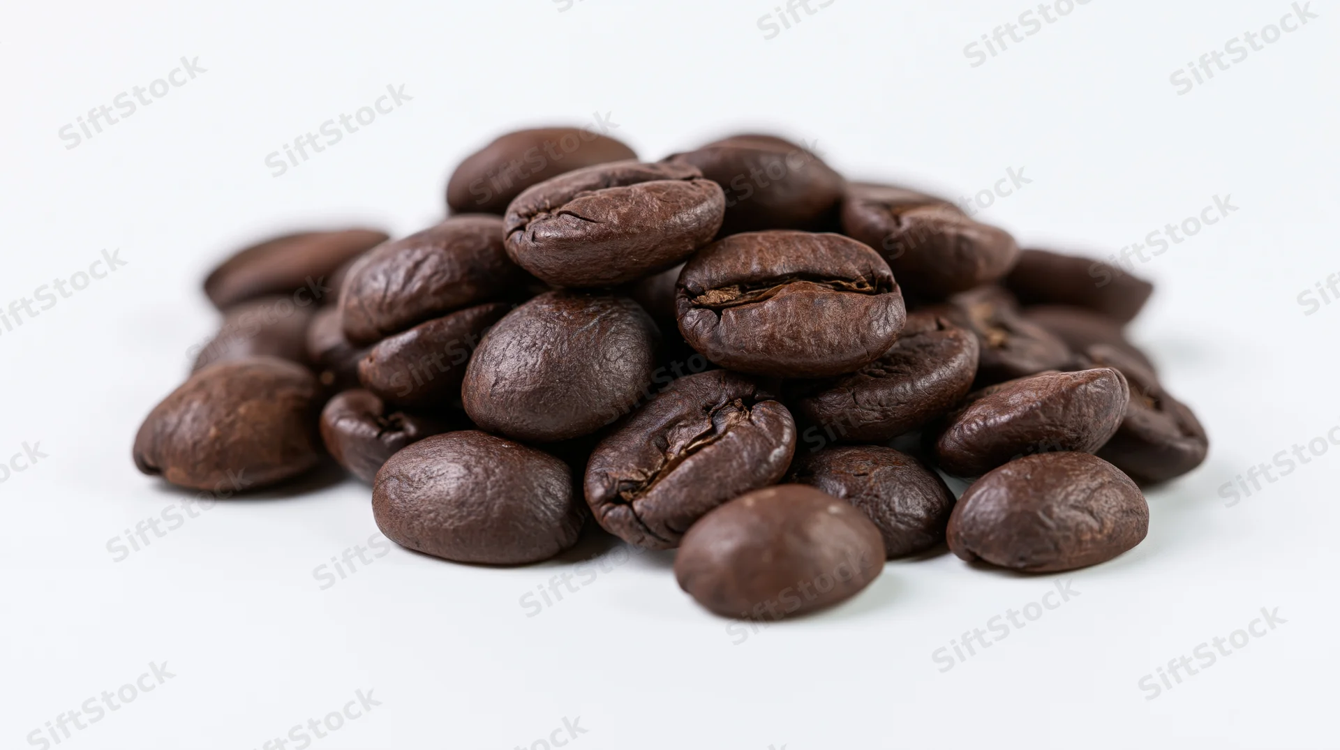 Small pile of dark roasted coffee beans on white background
