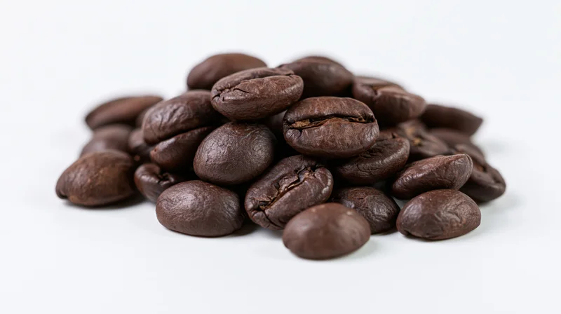 Small pile of dark roasted coffee beans on white background