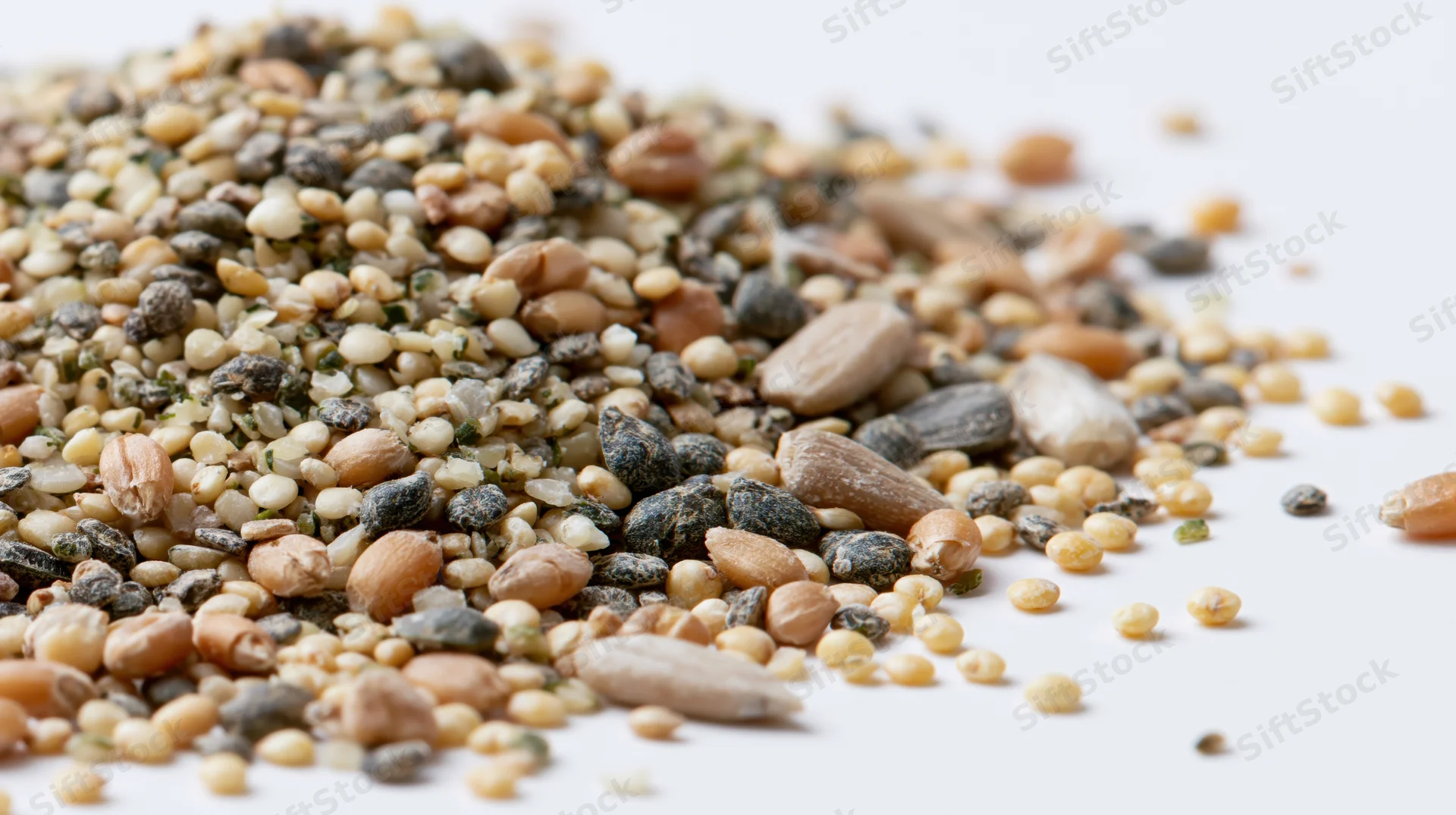 Scattered pile of mixed whole grains and seeds on white background