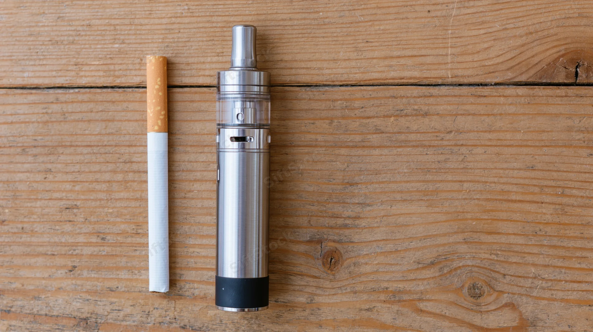 Traditional cigarette and vape pen placed side by side on wooden surface