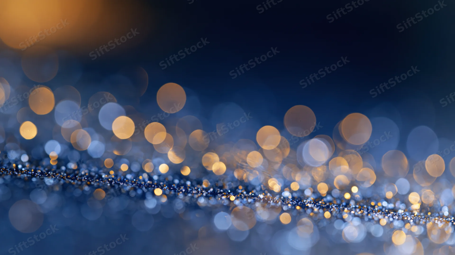 Abstract bokeh background with scattered soft glowing orbs of light in blue and golden tones