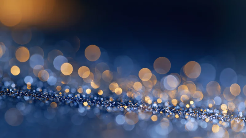 Abstract bokeh background with scattered soft glowing orbs of light in blue and golden tones