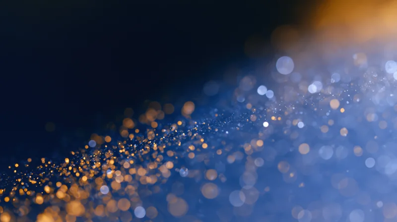 Abstract bokeh background with scattered soft glowing orbs of light in blue and golden hues