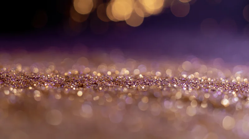Scattered gold glitter on a purple studio floor with bokeh lights in the background