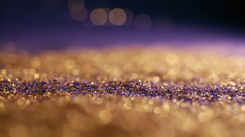 Gold and purple glitter scattered across a studio floor with bokeh lights in the background