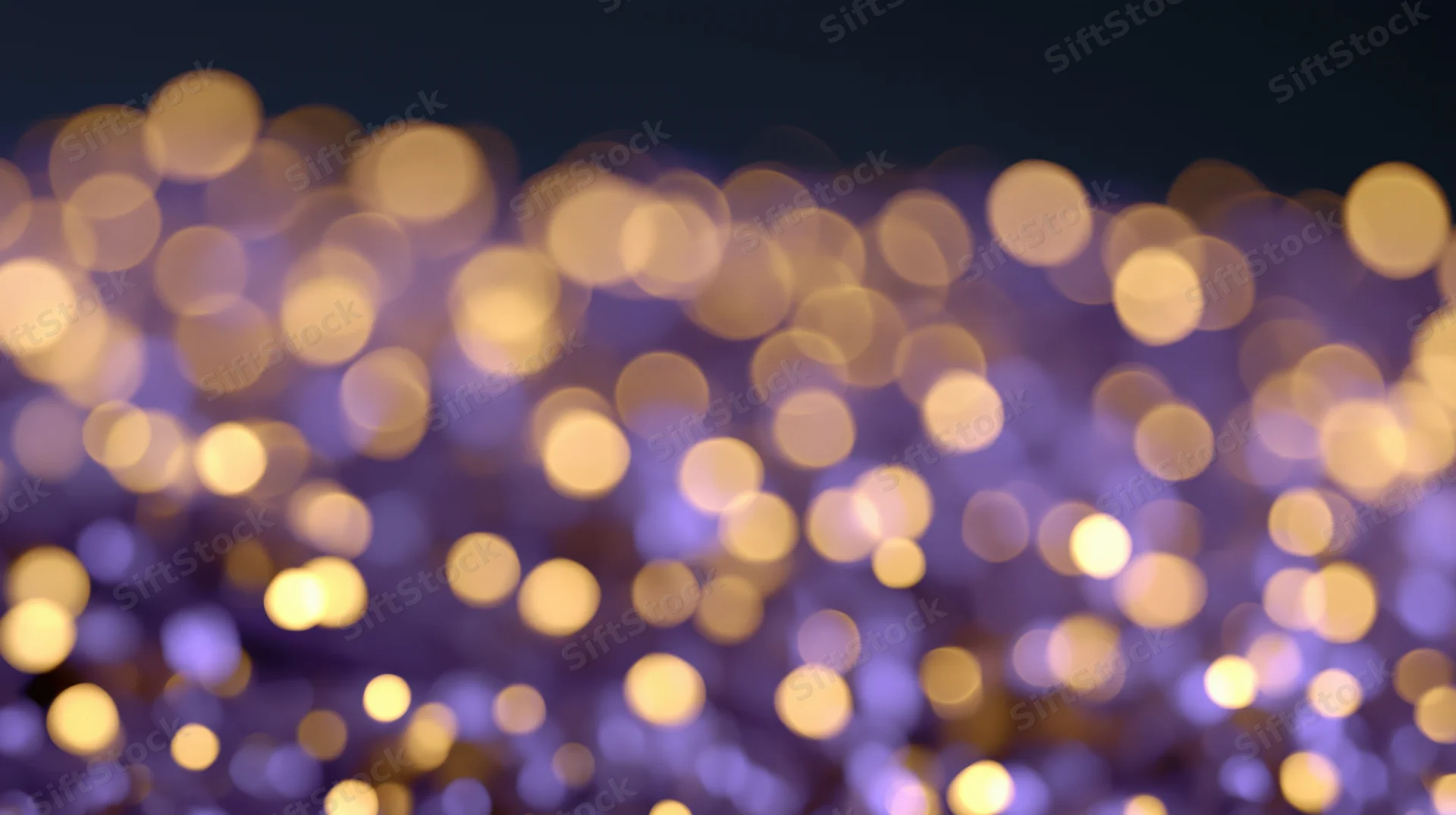 Blurred golden and purple lights creating a festive bokeh background at night