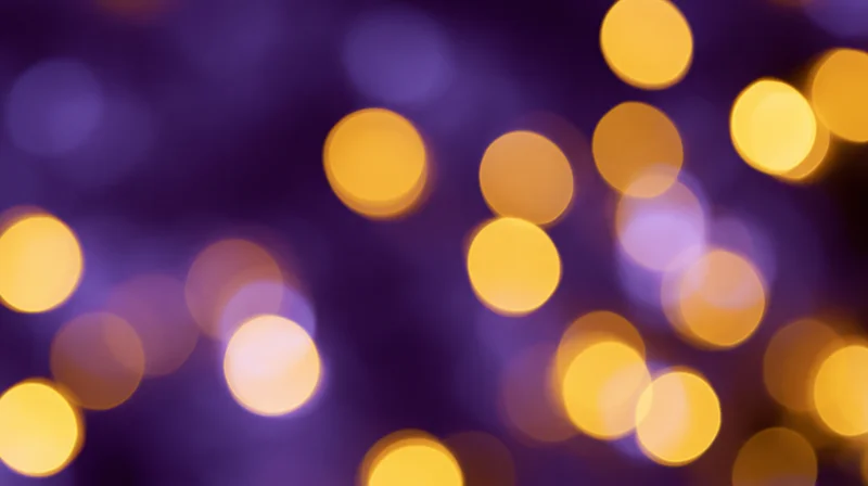 Abstract bokeh background with scattered golden lights on purple blur