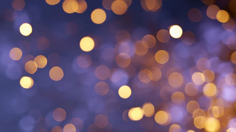 Abstract bokeh background with scattered golden lights on a dark blue gradient