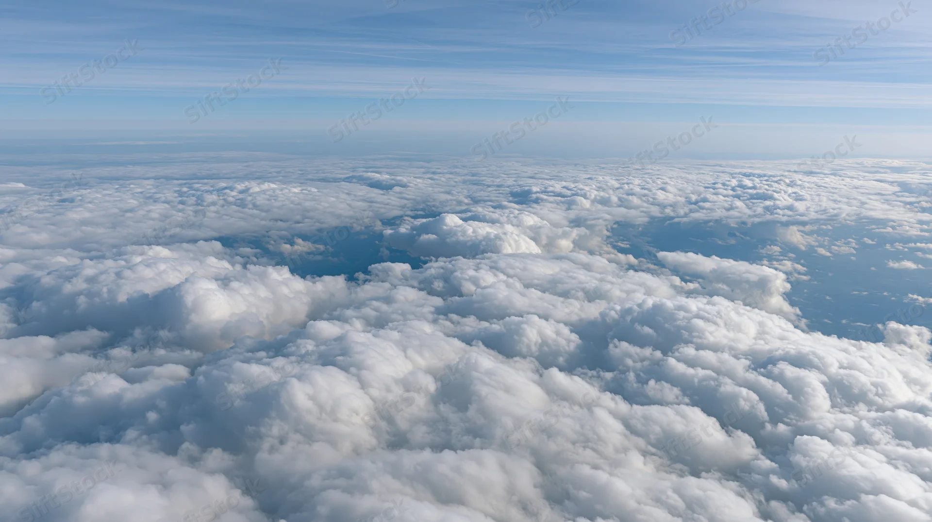 Aerial view above a dense layer of billowing cumulus clouds under a clear blue sky