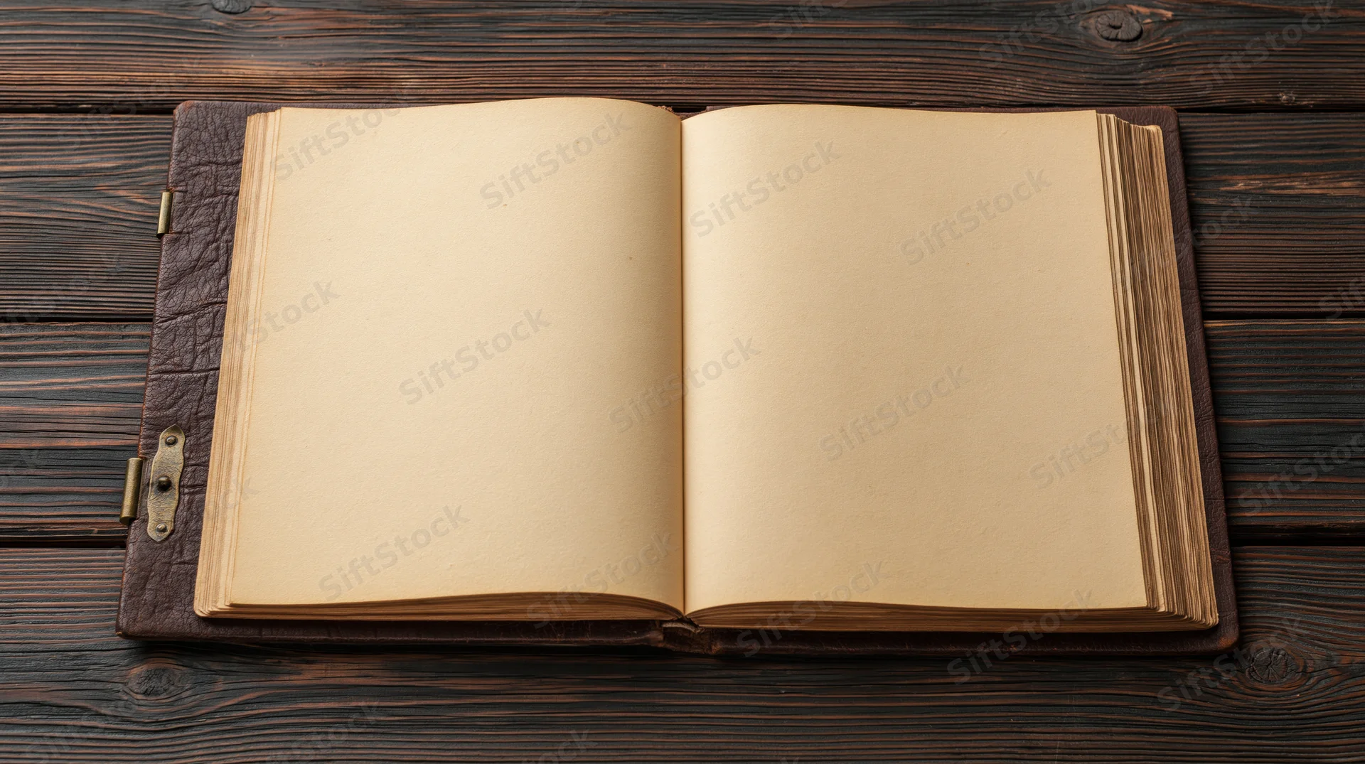 Open leather-bound book with blank yellowed pages lying flat on dark wooden surface