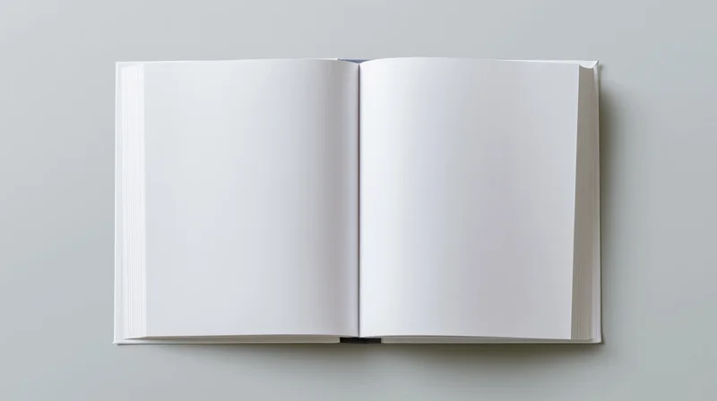 Open hardcover book with blank white pages lying flat on a gray surface