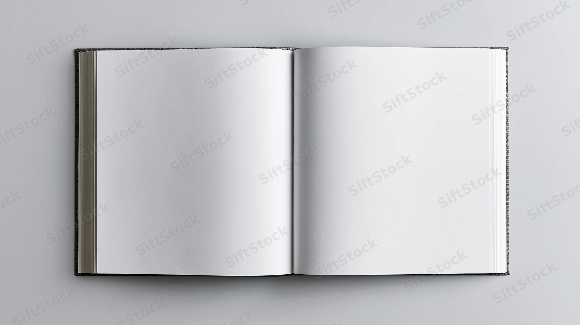Open hardcover book with blank white pages lying flat on a gray surface