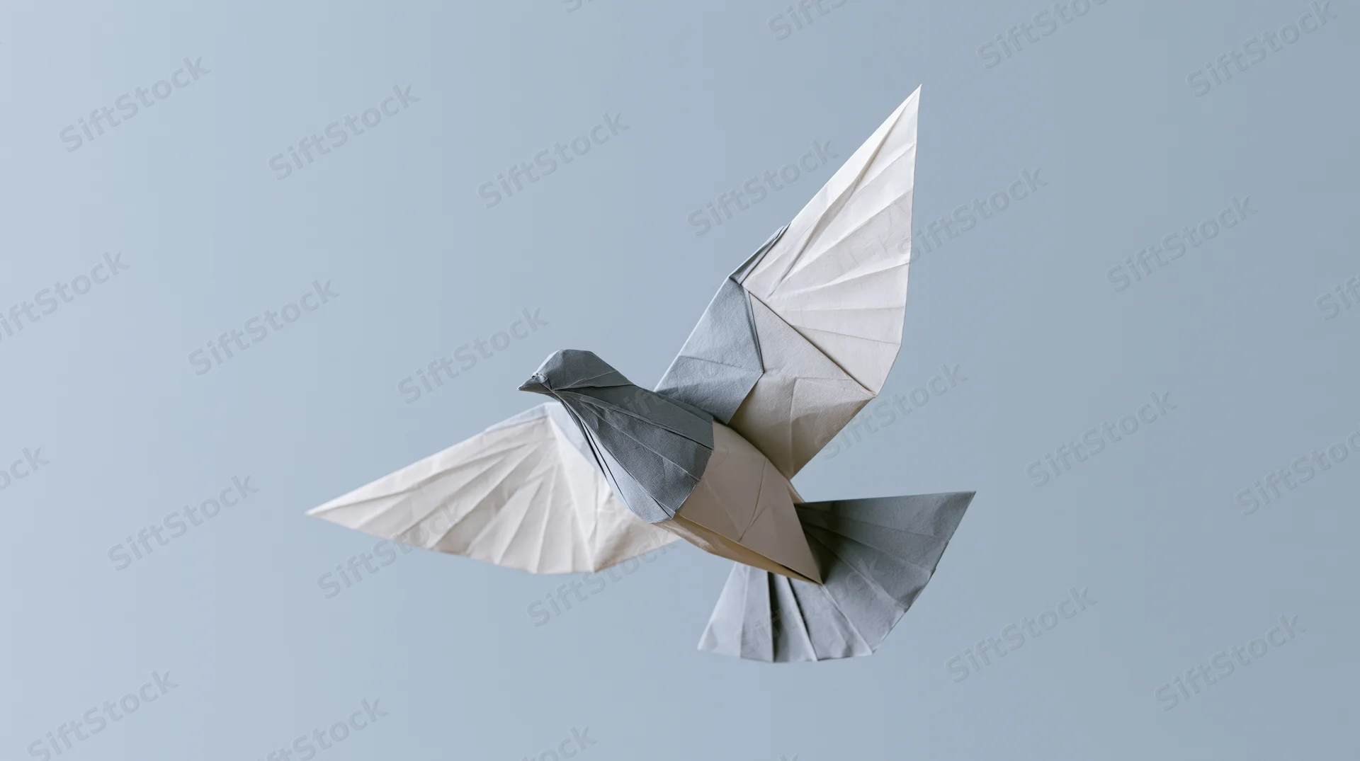 Origami dove in mid-flight with wings spread against a light gray background