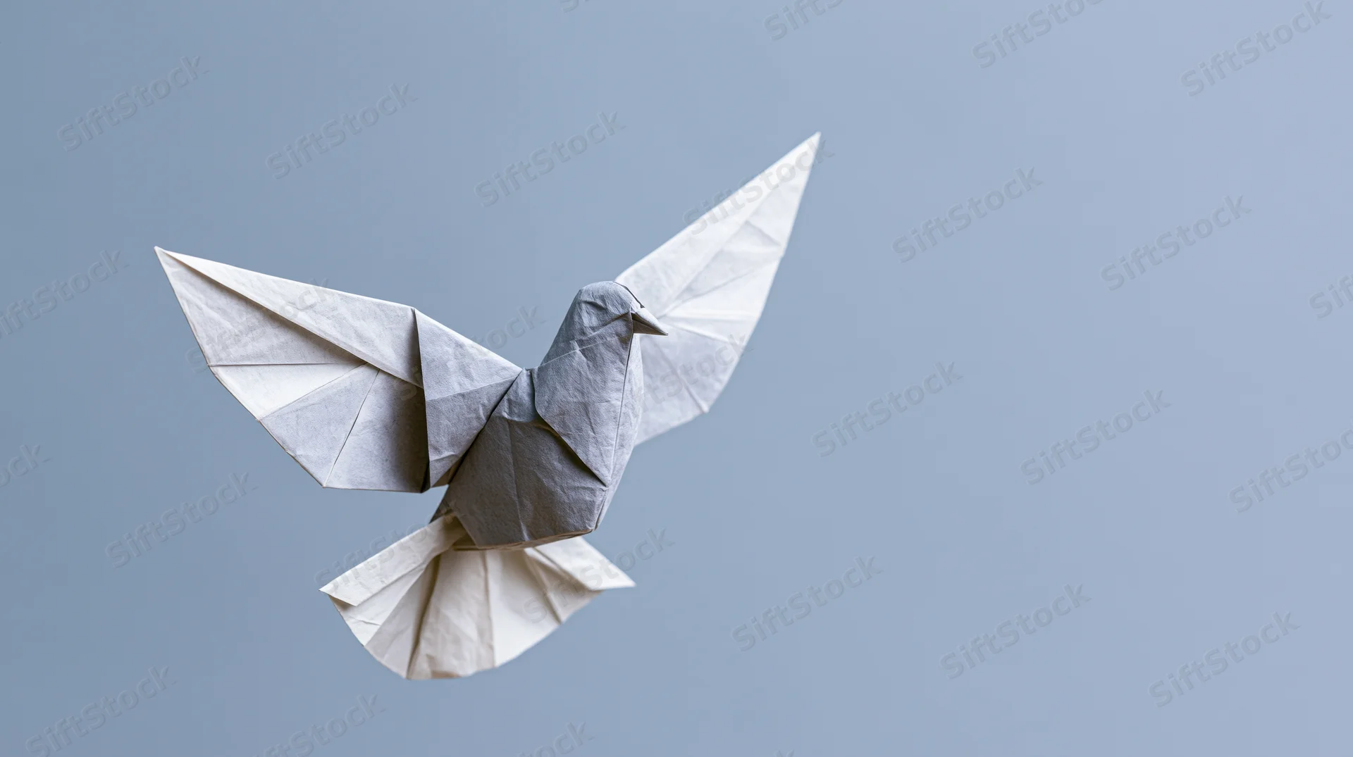 Origami dove with wings spread in midair against a plain blue background