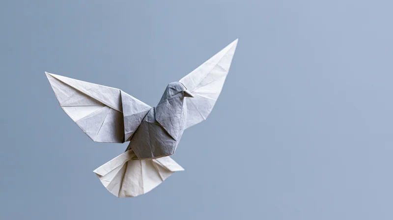 Origami dove with wings spread in midair against a plain blue background