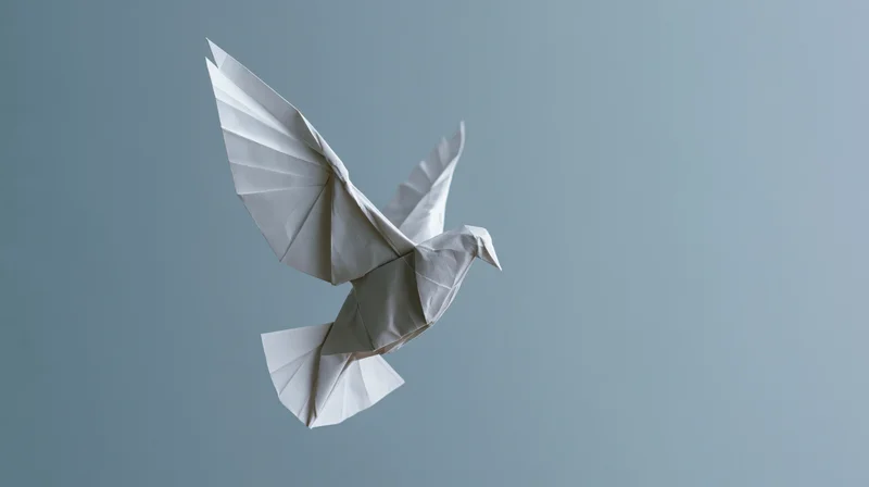 Origami paper dove in mid-flight with wings spread against a gray background