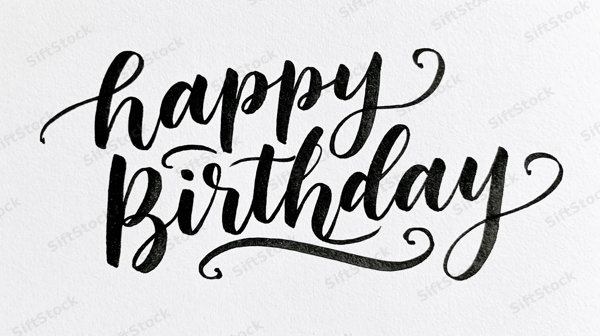 Black brush calligraphy reading happy birthday on white textured paper