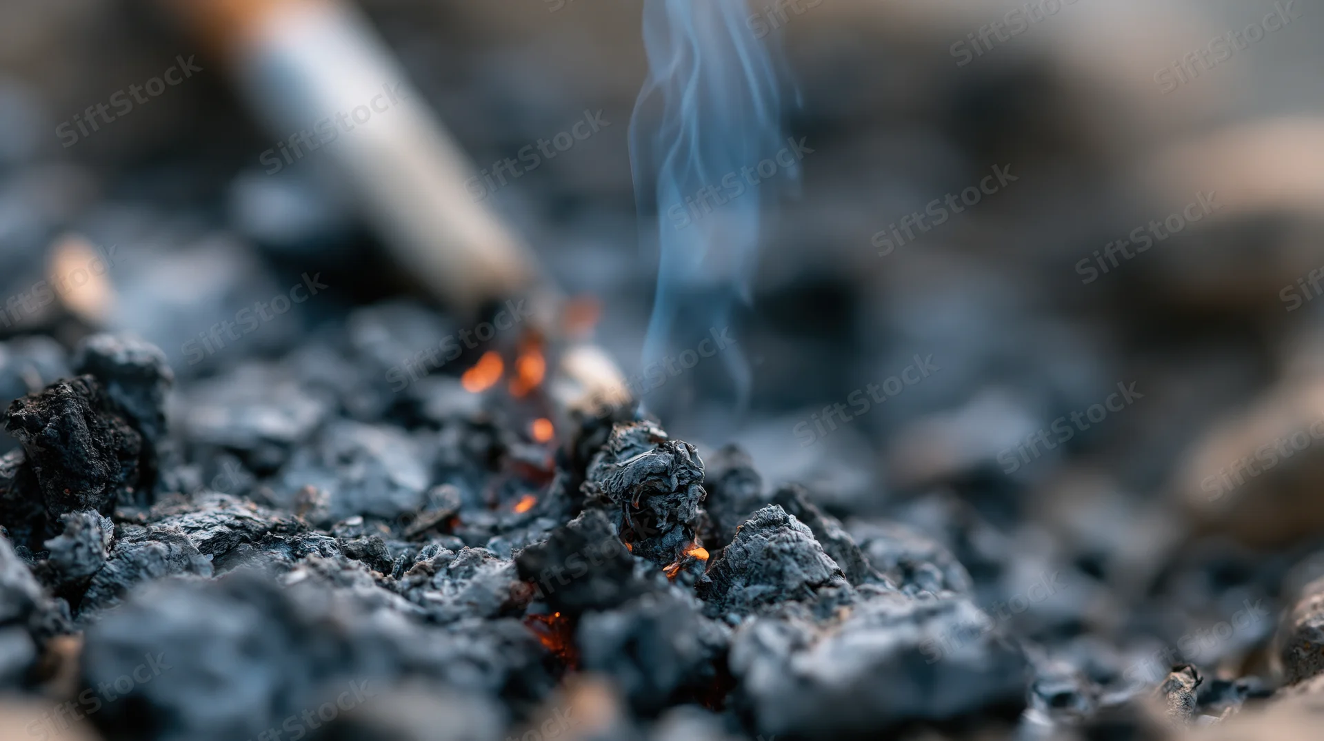 Cigarette stubbed out in ash and embers on ground