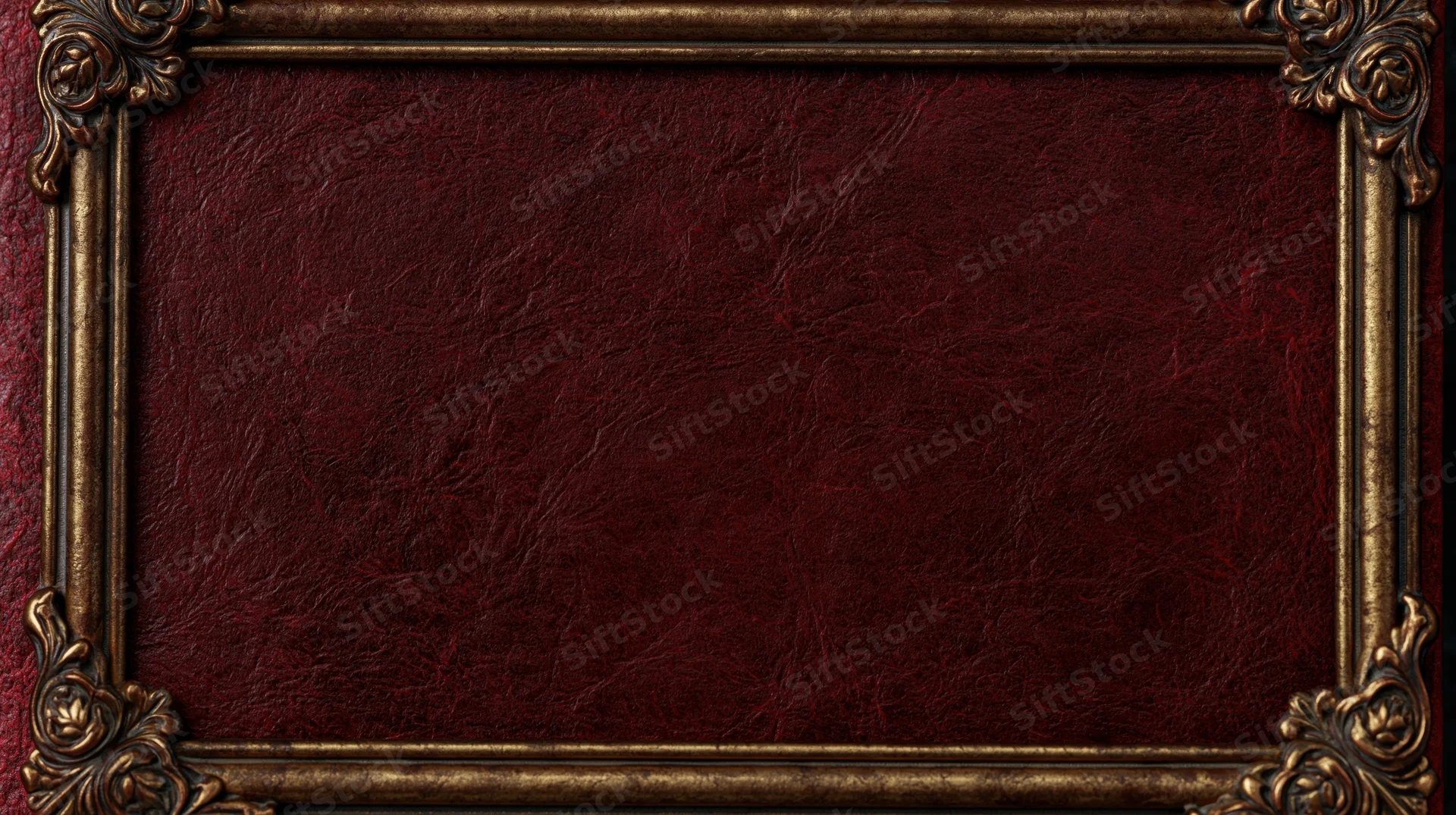 Close-up of an ornate gold frame surrounding a deep crimson textured leather book cover
