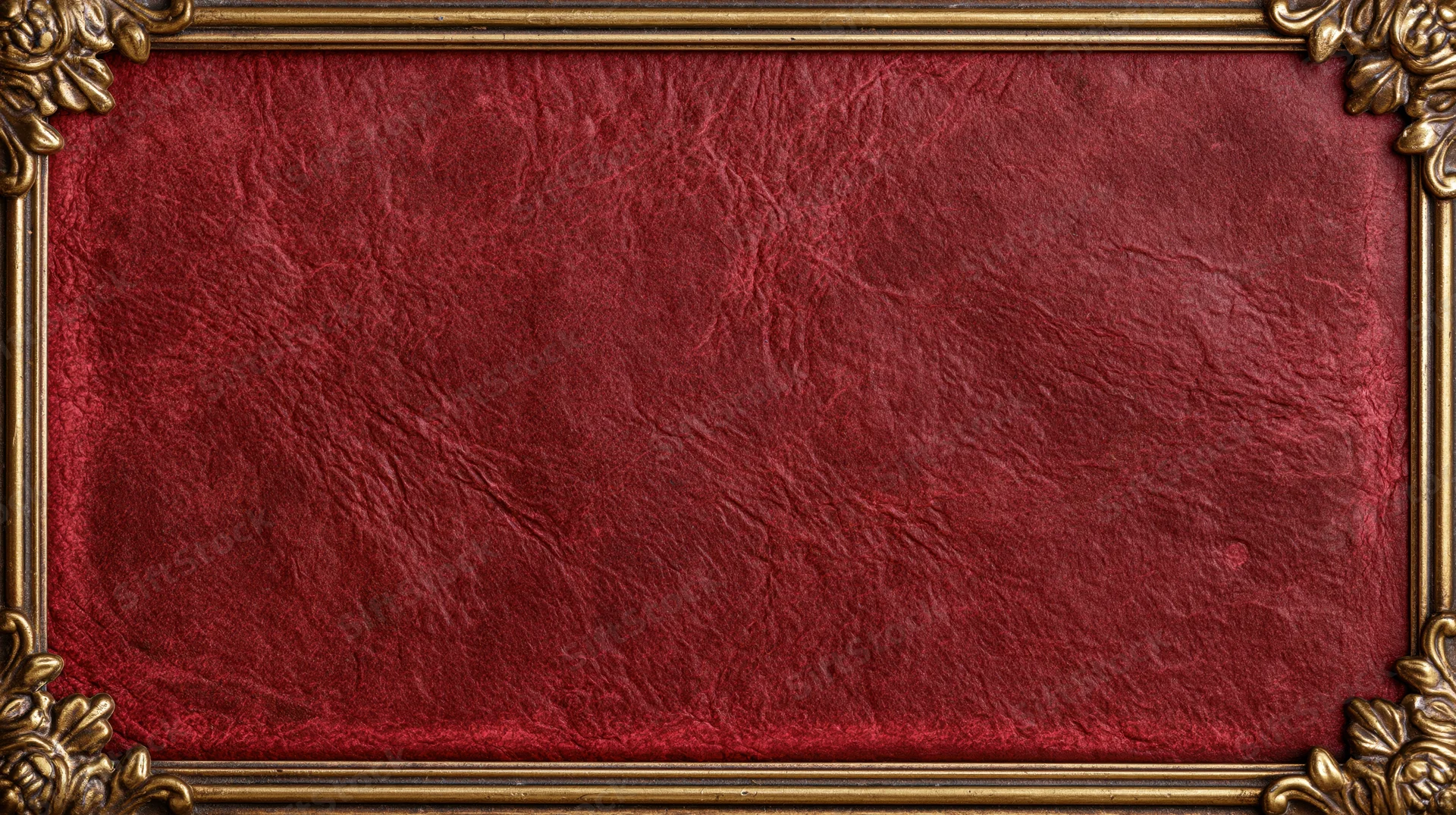 Ornate gold frame enclosing deep red textured leather book cover with floral corners