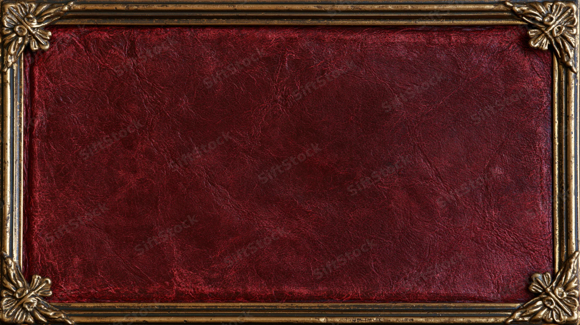 Aged crimson leather book cover with ornate gold frame and floral corners, flat lay view