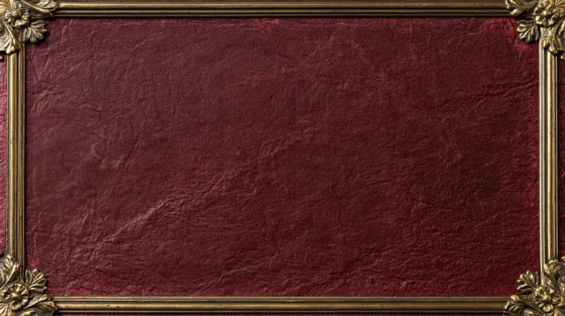 Close-up of an aged crimson leather book cover with ornate gold frame and floral corners