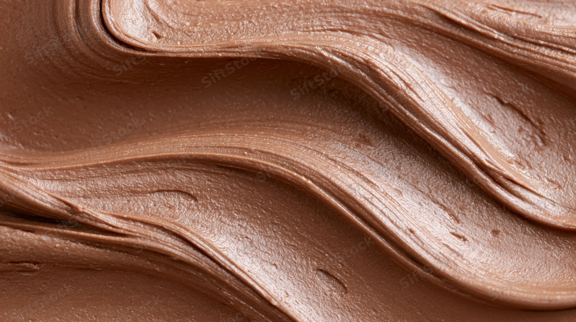 Close-up of smooth milk chocolate spread with swirling texture filling the frame