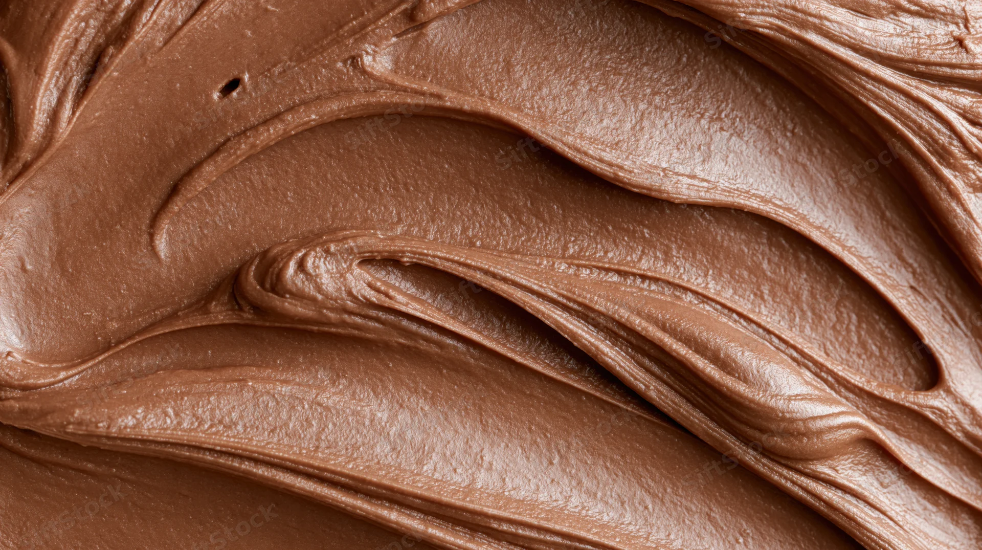 Close-up of smooth milk chocolate spread with swirling texture filling the frame