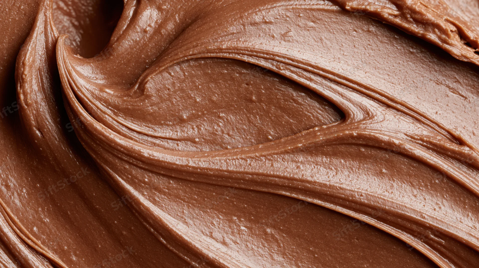 Close-up of smooth milk chocolate spread with swirling texture filling the frame