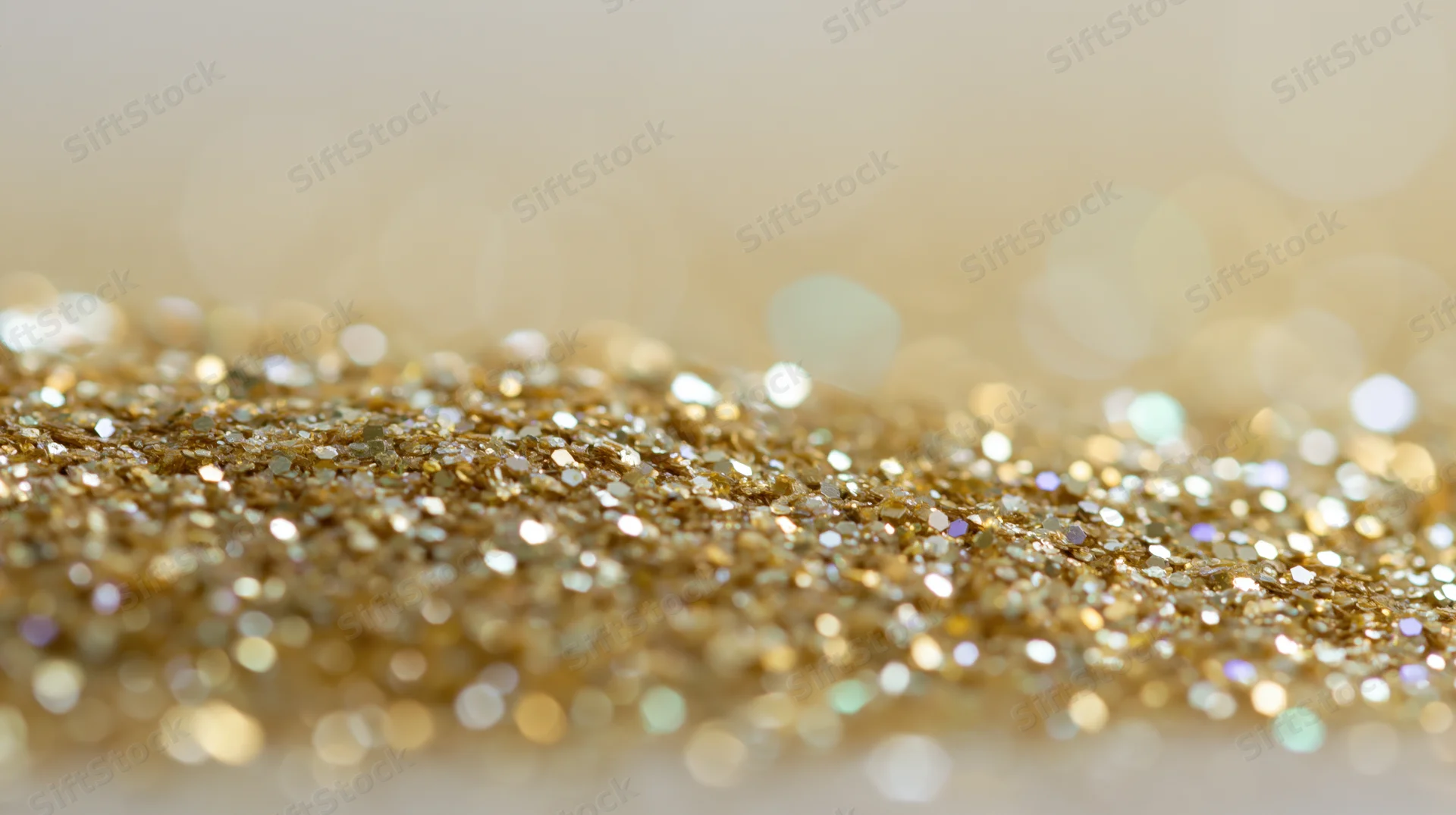 Close-up of gold glitter scattered across a surface with bokeh background