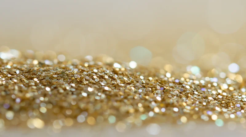 Close-up of gold glitter scattered across a surface with bokeh background