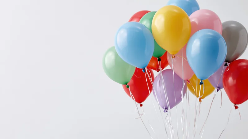 Cluster of colorful helium balloons floating against white background with copyspace