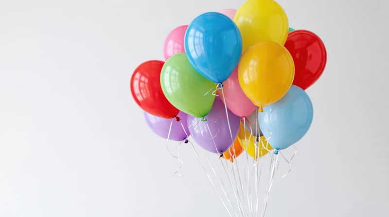 Cluster of colorful helium balloons floating against a white background with copyspace