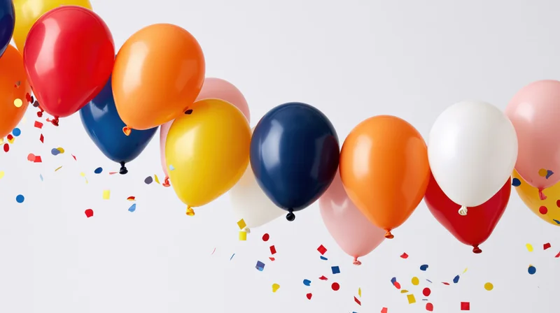 Colorful latex balloons floating midair with scattered confetti against white background