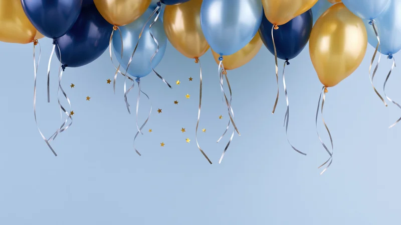 Cluster of navy blue, light blue, and gold metallic helium balloons with silver ribbons and star confetti against a light blue background, arranged across the top with copyspace below