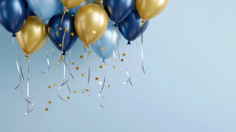 Cluster of navy blue, light blue and gold metallic helium balloons with ribbons and star confetti floating against a light blue background