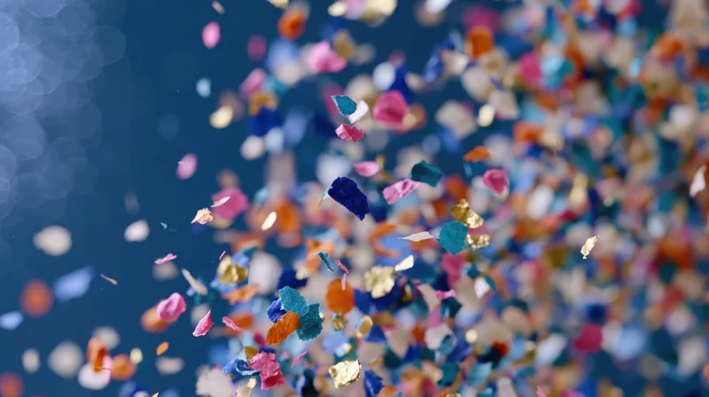 Colorful confetti pieces falling densely against a dark blue background