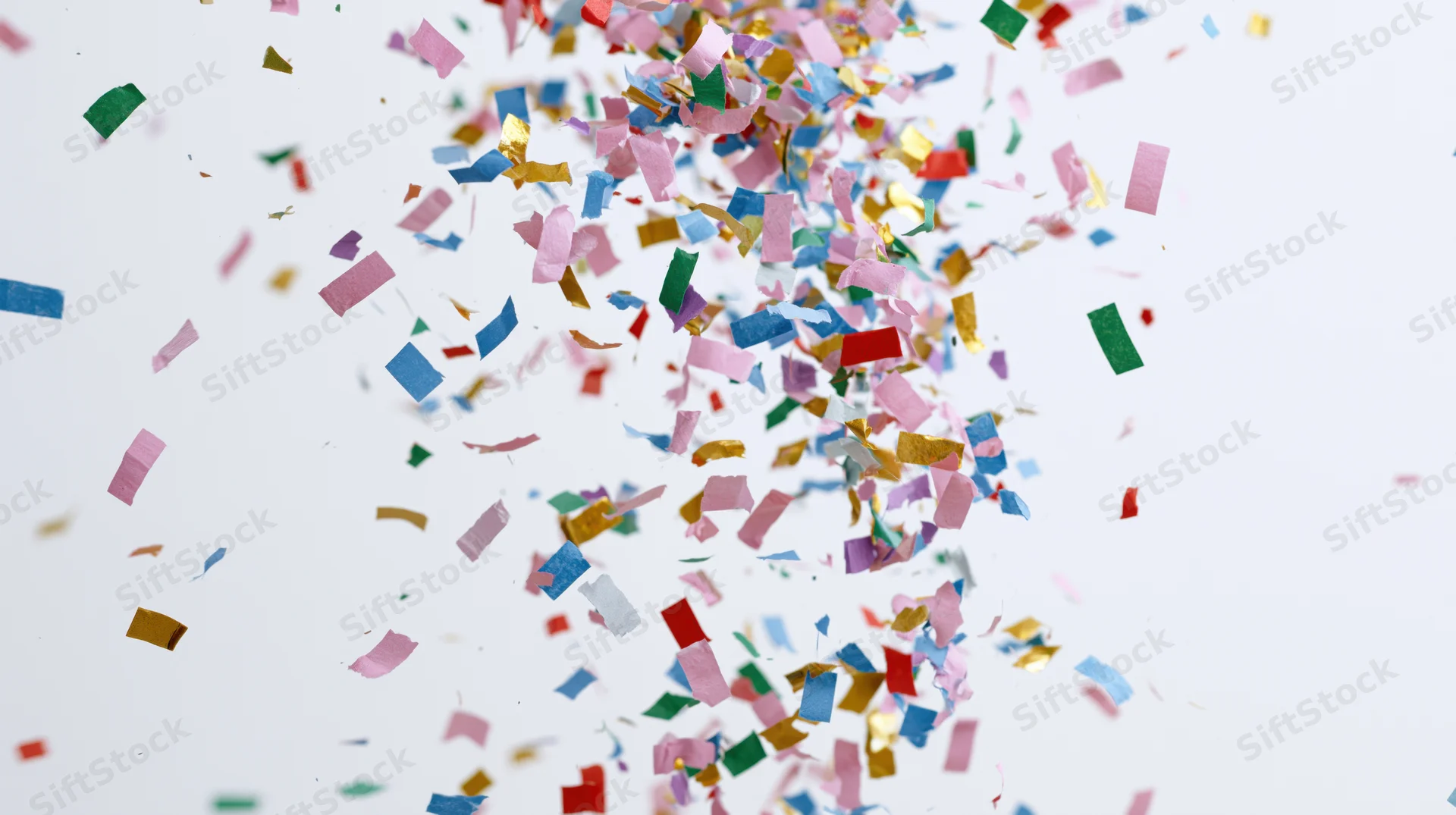 Colorful paper confetti pieces falling and floating mid-air against a white background