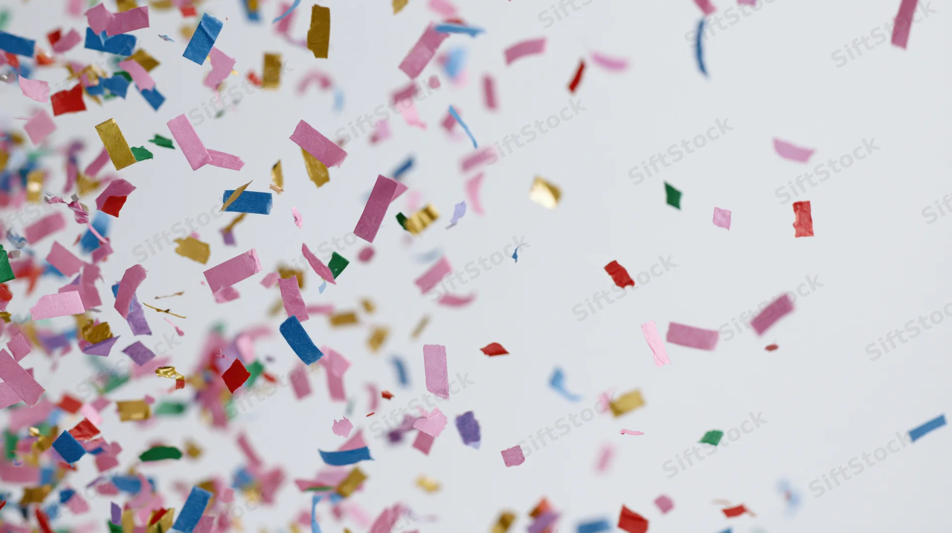 Colorful paper confetti pieces falling and floating mid-air against a white background